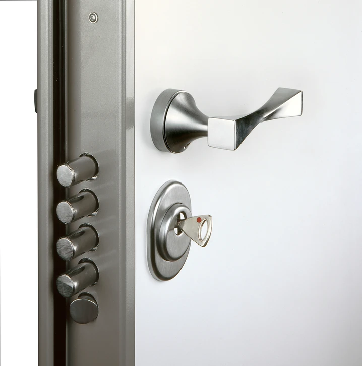 Porte d'entrée sécurisée avec serrure multipoints visible, poignée en acier inoxydable et clés insérées